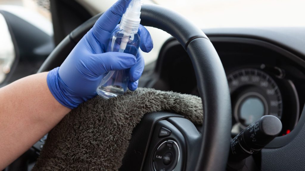 A man in gloves cleaning the steering wheel